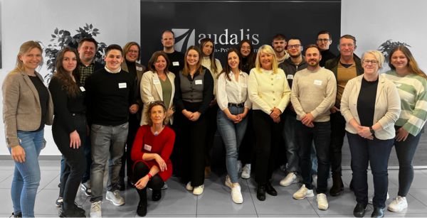 Die Beteiligten der Veranstaltung stehen im Eingangsbereich bei audalis